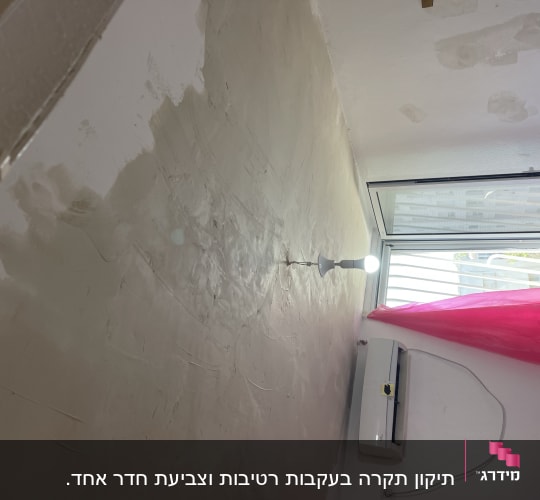 קיר מטויח עם תיקונים, מנורה דולקת, חלון פתוח